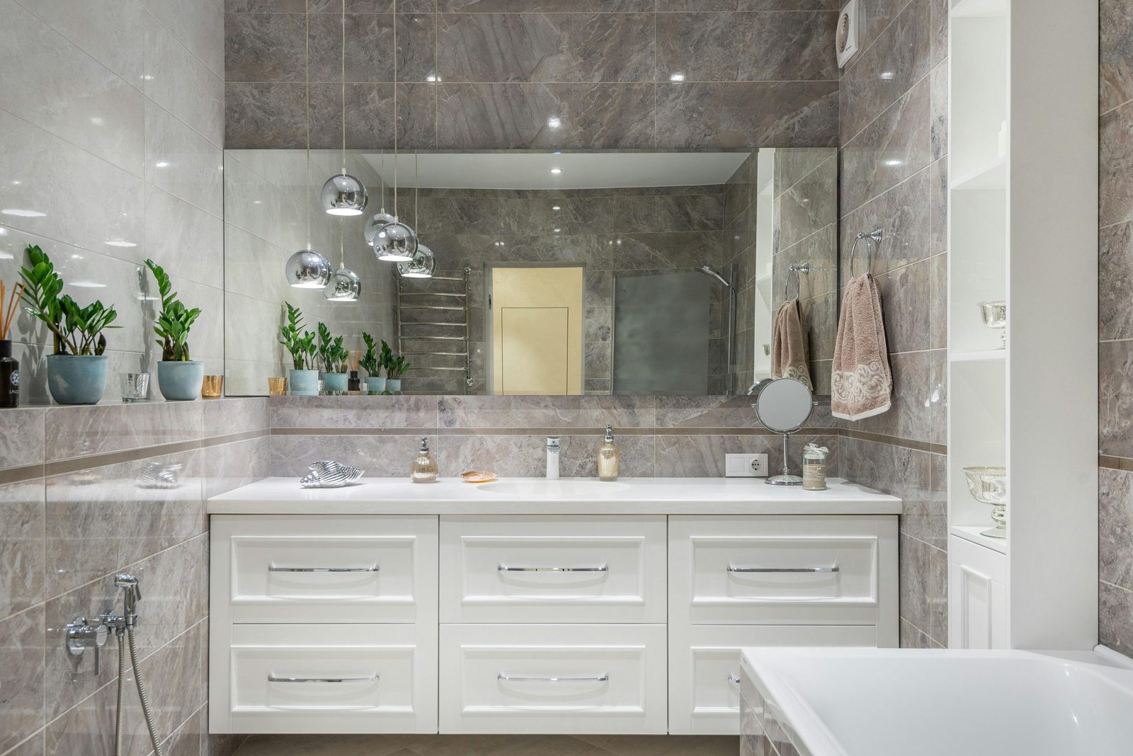 Modern bathroom with grey stone-look tile, a wide white vanity and a large mirror