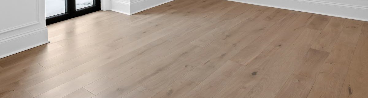 Wide-plank wood-look flooring meeting white walls and a black-framed glass door