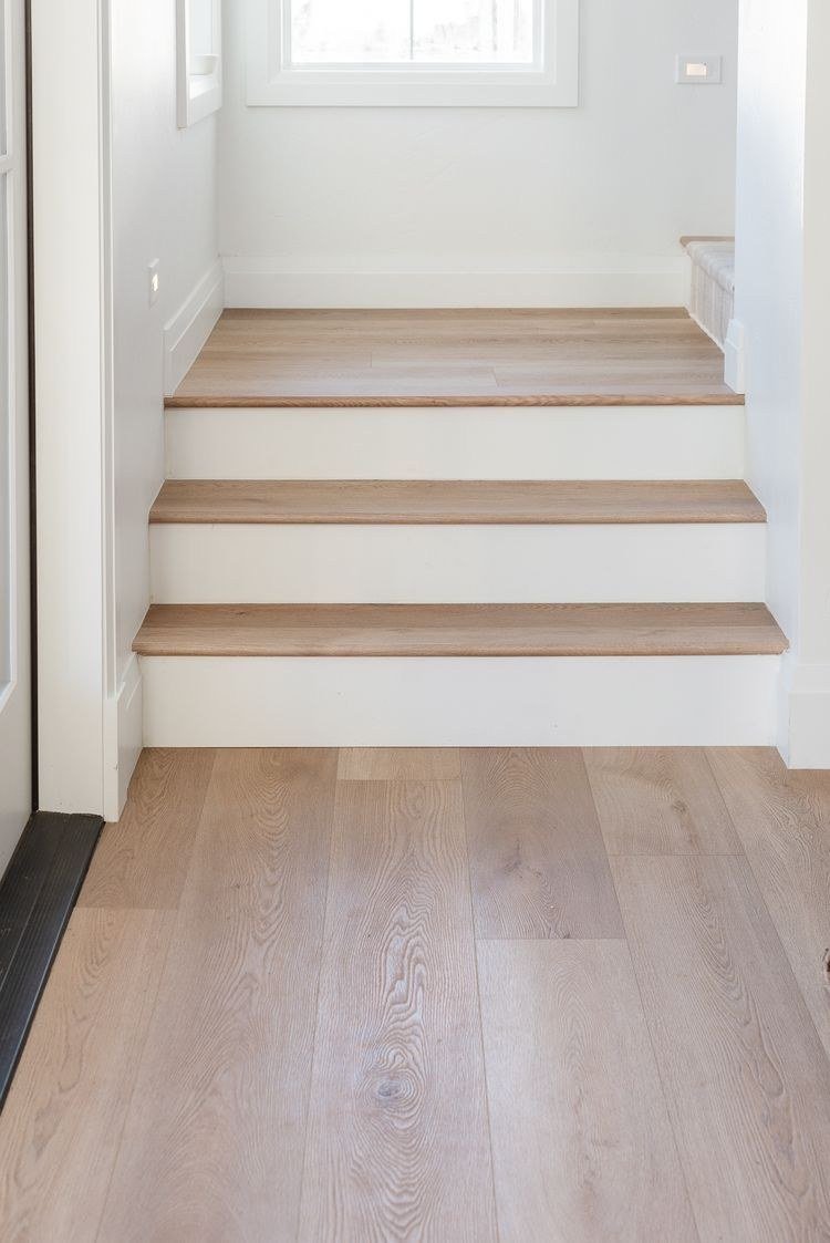 Light wood-look plank floor leading up three stairs with white risers