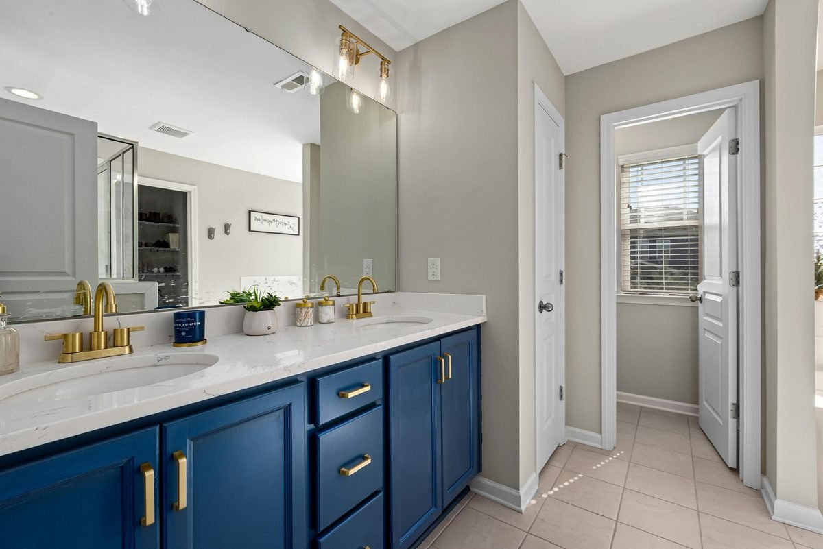 Bathroom vanity with gold fixtures and a doorway to a bright hallway