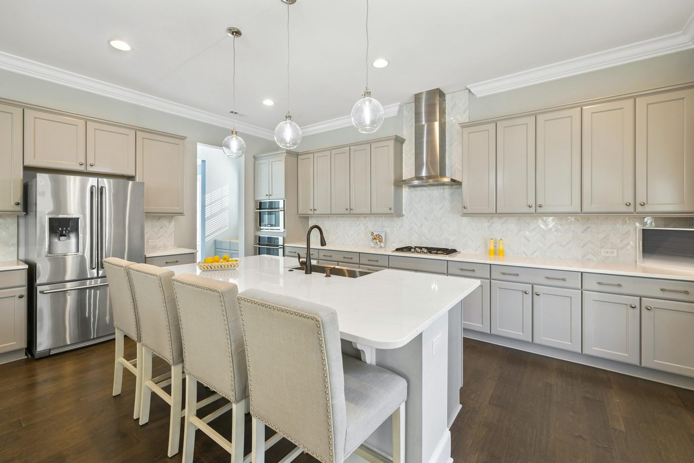 Kitchen with glass pendant lights, grey cabinets and a stainless steel range hood