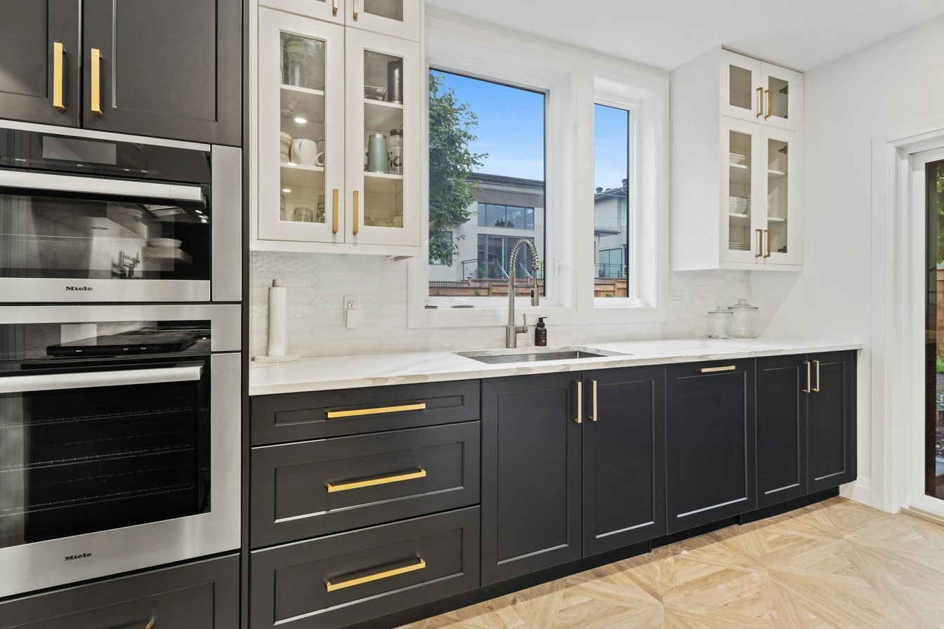 Kitchen cabinets with gold hardware and a bright window