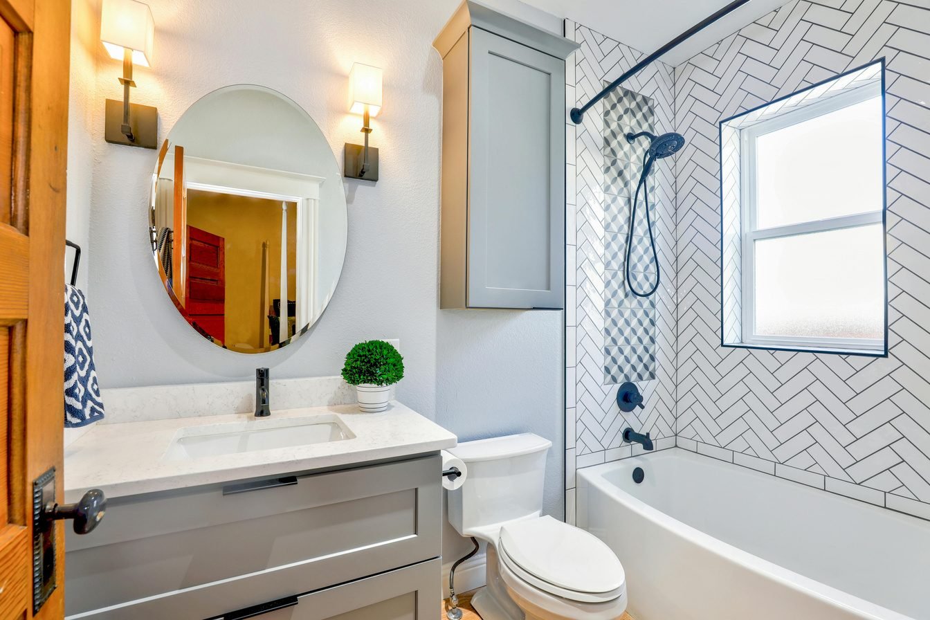Bathroom with a round mirror, wall sconces and a white vanity