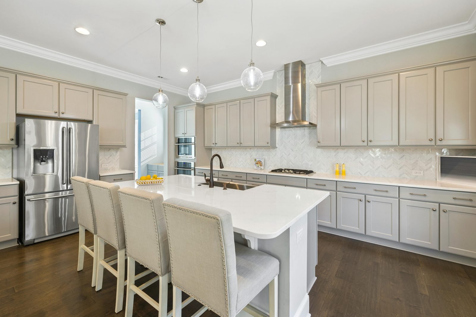 Large kitchen with grey shaker cabinets, a quartz island and glass pendant lights