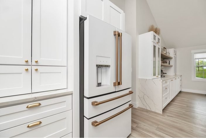 White shaker cabinets with copper handles beside a white refrigerator