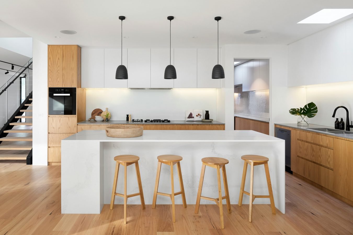 Bright remodelled kitchen with a white waterfall island, oak cabinetry and pendant lights